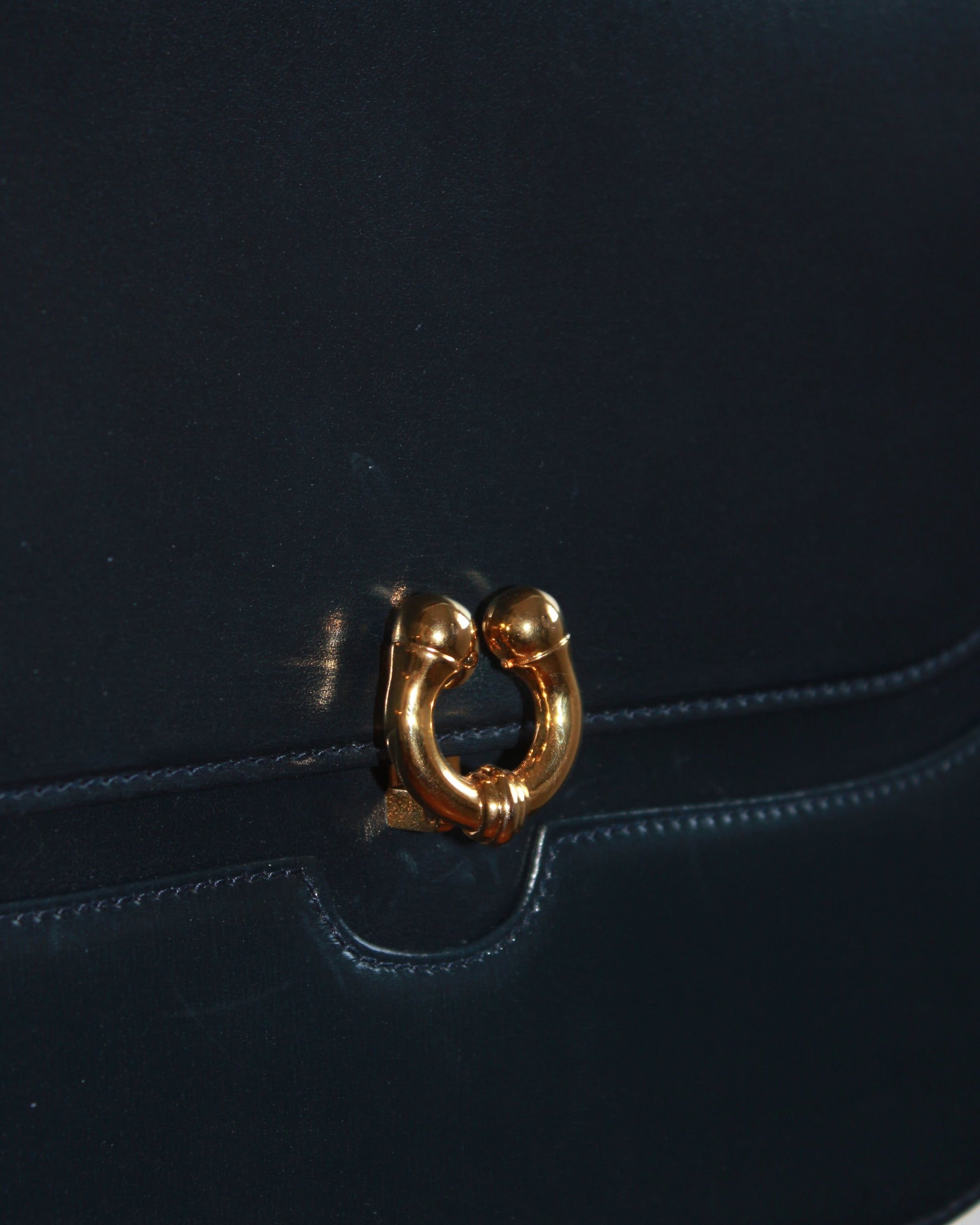 closeup of clasp on vintage navy gucci calfskin handbag with gold hardware