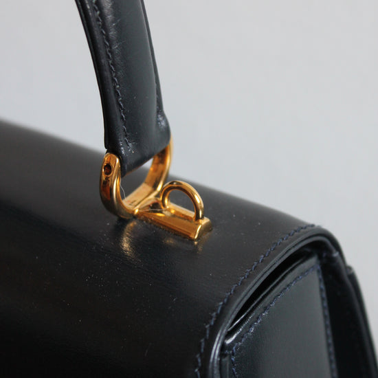 detail of golden hardware to attach crossbody strap on vintage navy gucci calfskin handbag