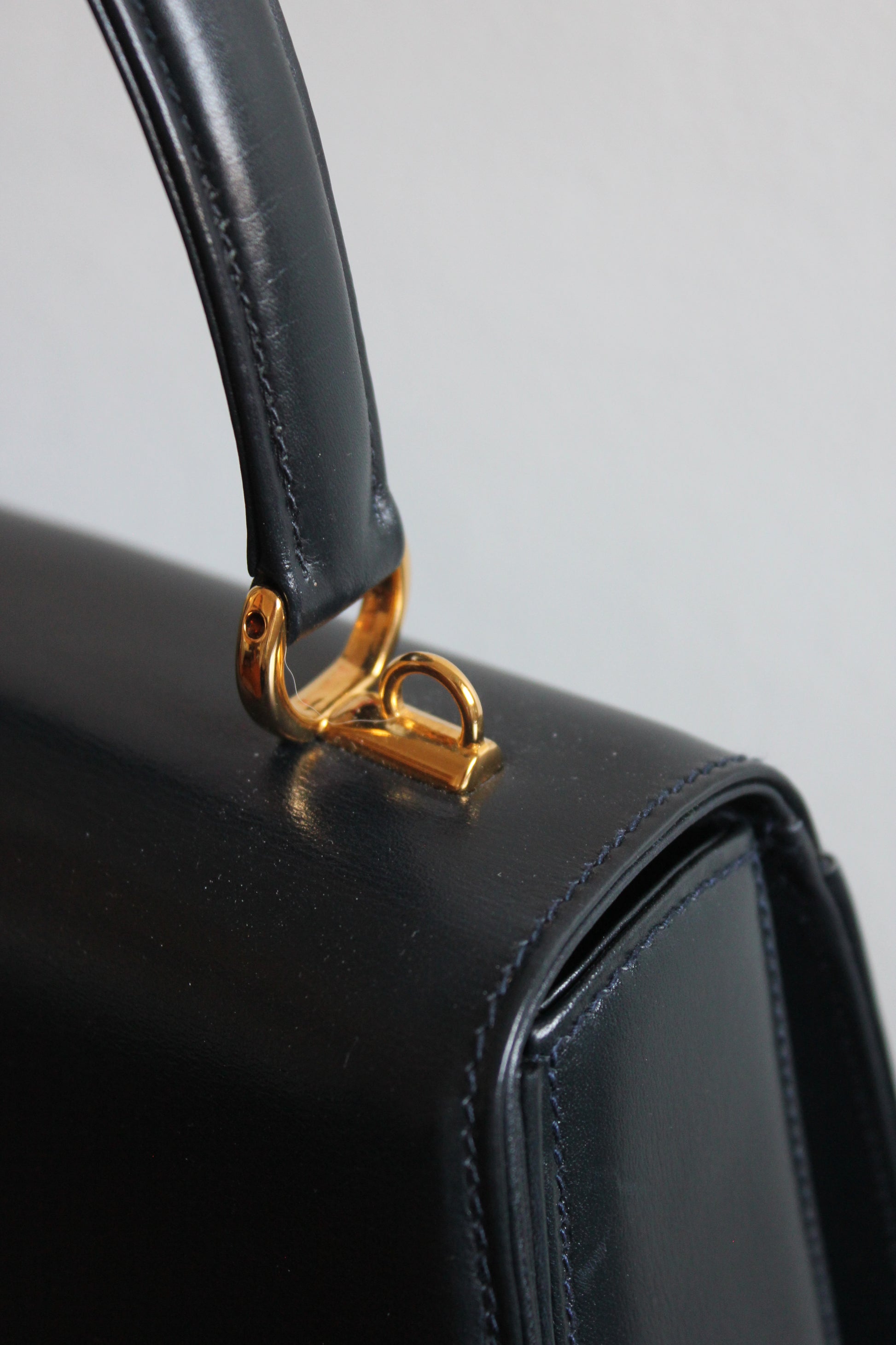 detail of golden hardware to attach crossbody strap on vintage navy gucci calfskin handbag